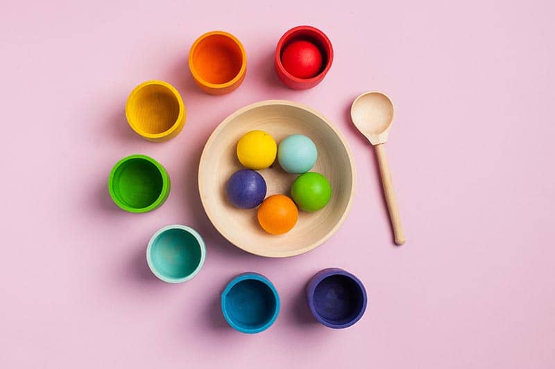 photo example of messy art-based activities for kids, kids sized cups made out of clay displayed in order of the color spectrum.