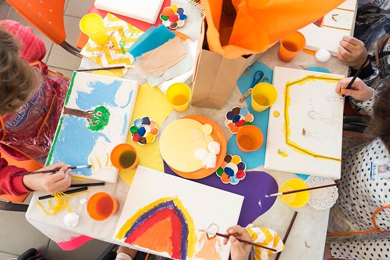 overview pic of kids drawing and painting at a table