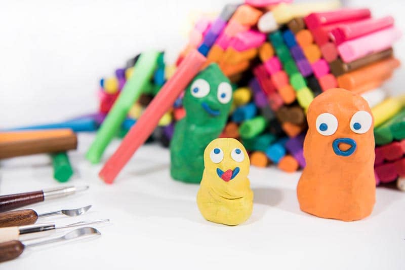 goofy clay figurines surrounded by art supplies