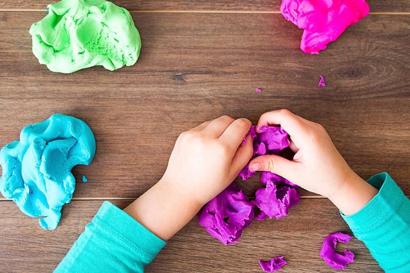 a kid's hands working with colorful clay