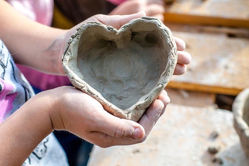 image of a kid holding a heart-shaped clay object