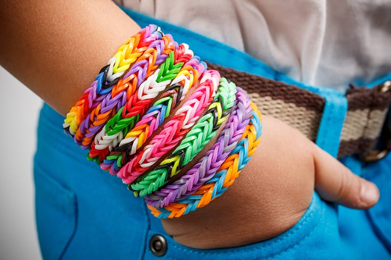 image of a kid's hand wearing numerous colorful handmade bracelets